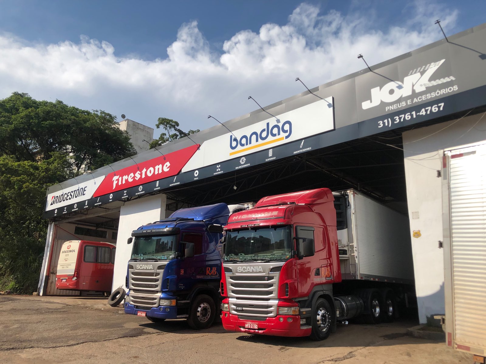 Fachada da JOAZ Pneus na BR-040, com dois caminhões Scania em atendimento sob a cobertura